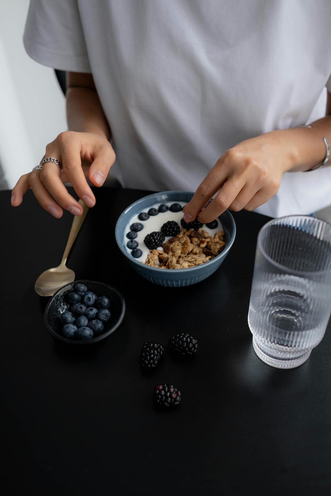 High-angle shot of a person preparing a berry and granola breakfast, emphasizing healthy eating.