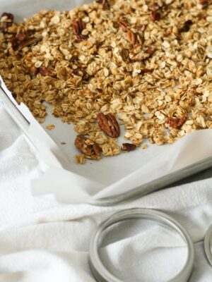 Homemade granola with oats and pecans fresh from the oven on a baking tray.